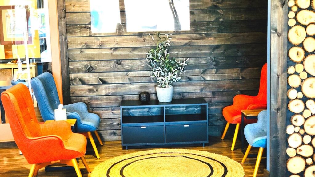 Lounge corner with orange chairs and a log-slice wall